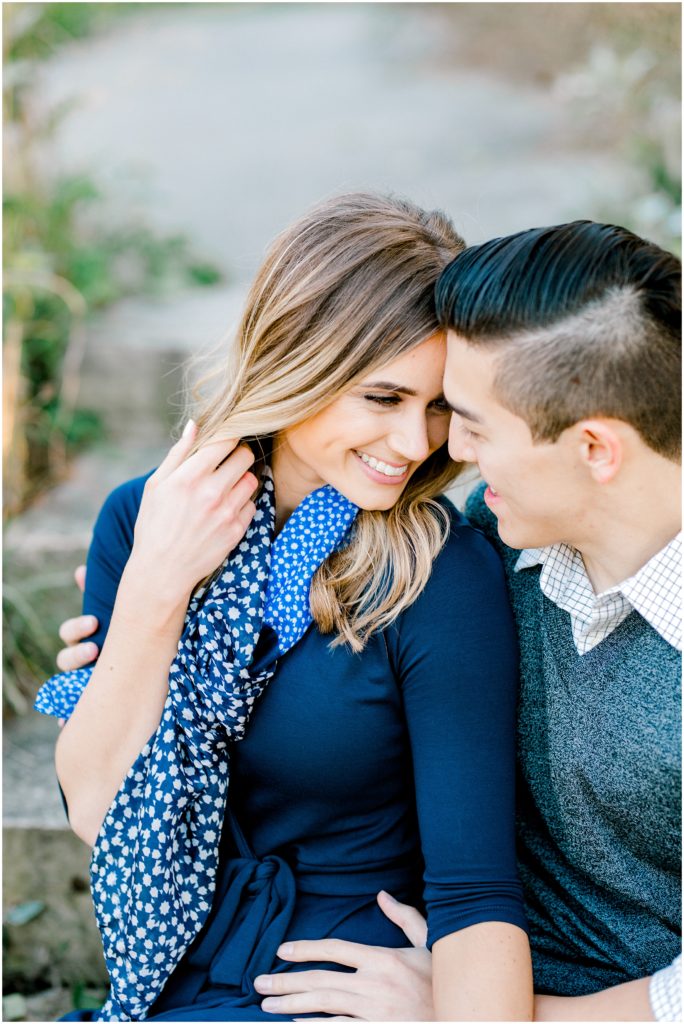 couple's engagement session , looking at each other and smiling she is holding her hair
