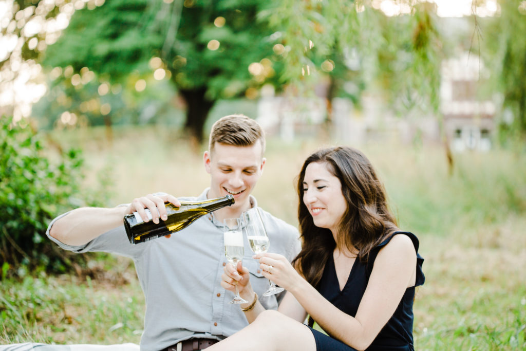 guy is pouring champagne during the engagement session
