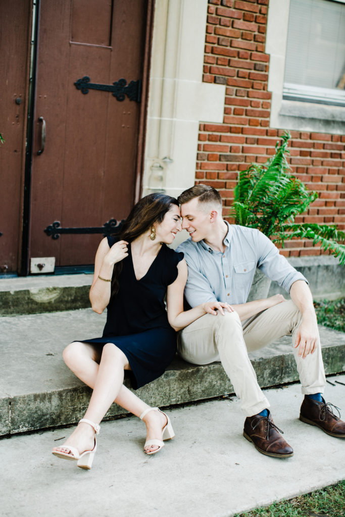 man and woman sitting on the stairs touching each others backs and almost kissing, engagement session pictures,