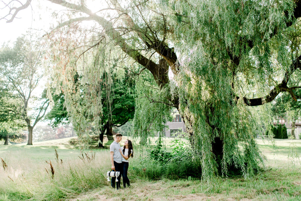 couple standing under weeping willow and looking at each other