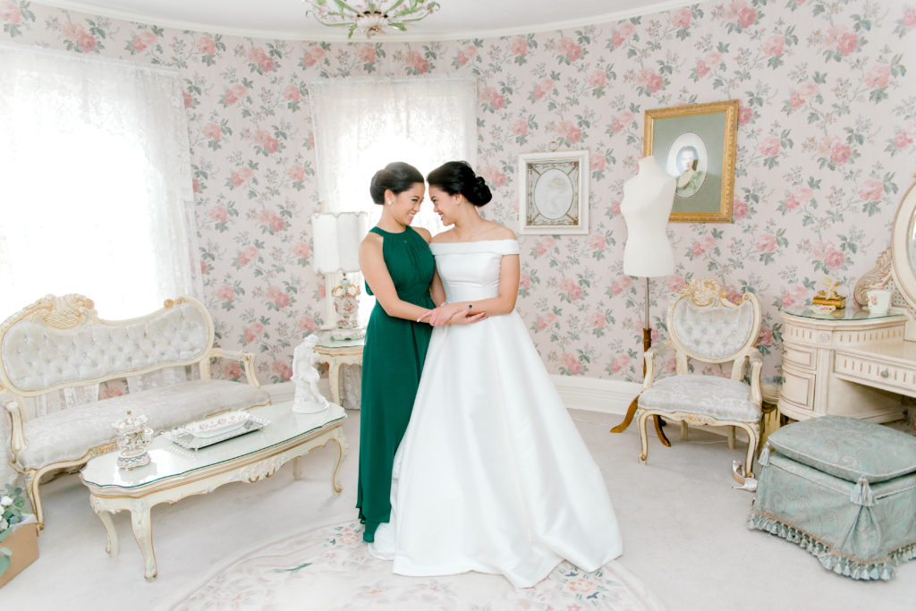 bride and one bridesmaid hugging and touching their foreheads in the getting ready room at Haley Mansion