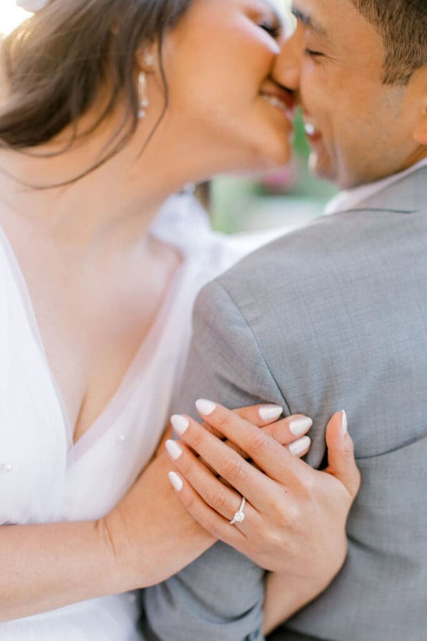 Close-up of engagement ring on the bride’s hand, surrounded by colorful garden flowers.