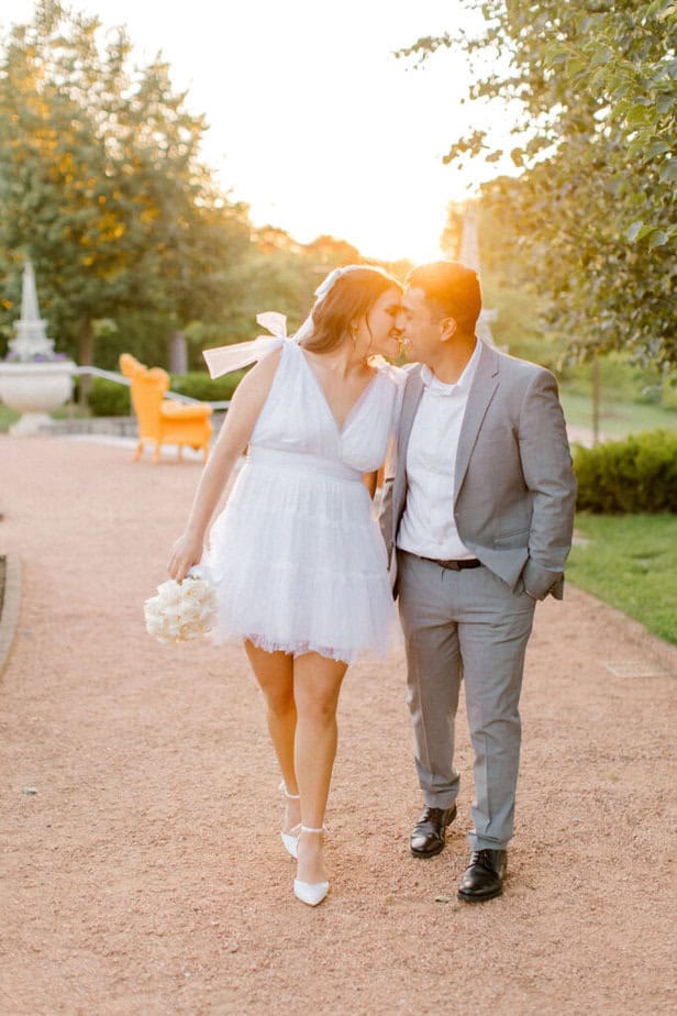 Candid shot of the couple walking along a tree-lined path, the sun shining through the leaves.