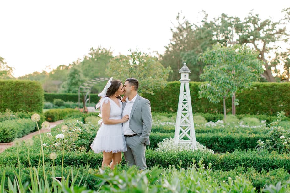 Romantic photo of the couple standing together under an archway covered in vines and flowers.