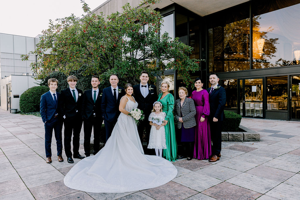 Extended family grouped together outdoors, smiling for a portrait”