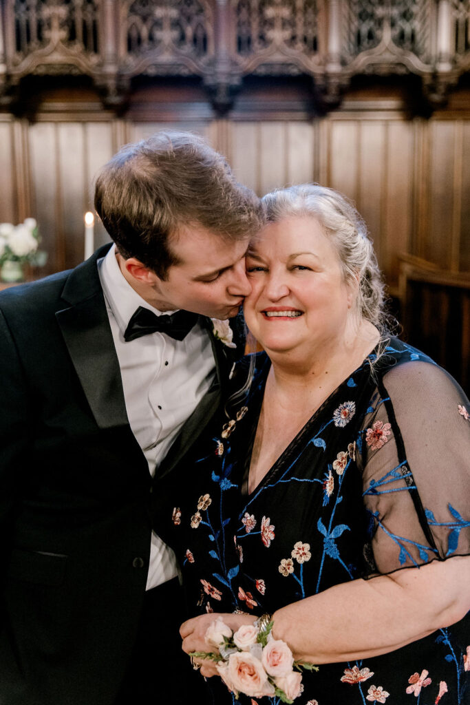 Groom giving his mom a kiss on the cheek during portraits